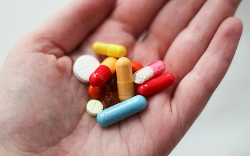 orange and white medication pill on persons hand